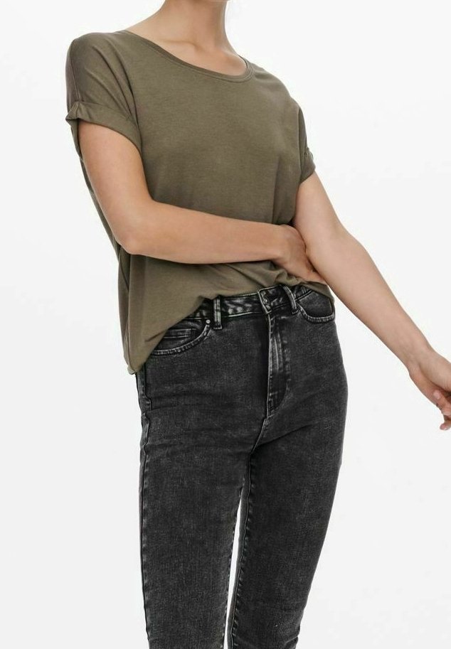 Personne portant une chemise manches courtes vert olive rentrée dans un jean noir délavé taille haute, sur un fond blanc uni.