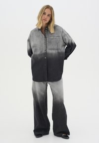 Denim öltözet, amely egy szürke-fekete ombre gombos ingből és hozzáillő, elől zsebes, harangszárú nadrágból áll. Texturált anyag.
