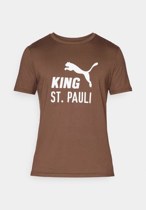 Smeđi pamučni T-shirt sa bijelim grafičkim printom. Natpis "KING ST. PAULI" s logotipom skakutajuće pantere iznad. Kratki rukavi, okrugli izrez.