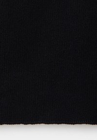 Gros plan d'un tissu tricoté côtelé noir avec texture visible et bords sur fond blanc.