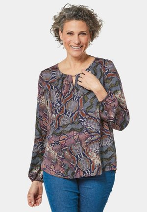 Langärmlige Bluse mit multicoloriertem abstraktem Muster. Sie hat einen runden Ausschnitt mit einer kleinen Schlüssellochöffnung und elastischen Manschetten.