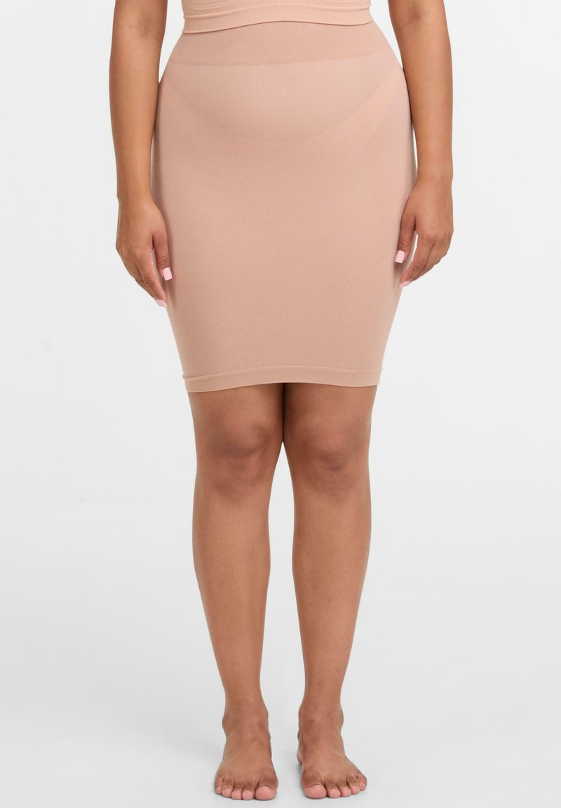 Beige form-fitting stieptas svārki ar gludu tekstūru, ceļa garuma dizains un plaša, bezšuvju josta papildu komfortam.