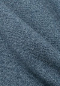 Blått tyg med en mjuk, strukturerad yta, som har ett subtilt, enhetligt mönster. Materialet verkar vara en fin ull eller en blandning.