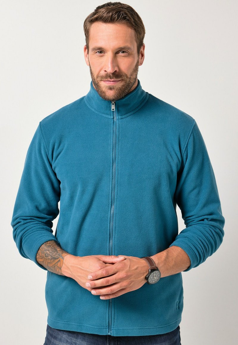 Giacca in fleece verde acqua con colletto alto, zip frontale completa e maniche lunghe. Presenta polsini a coste e un dettaglio del logo discreto sull'orlo.