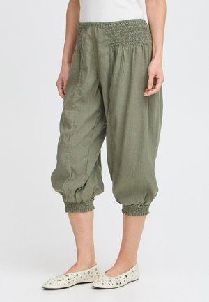 Pantalons harem en lin vert olive avec une taille froncée, des poignets froncés et des poches latérales, en tissu léger et texturé.