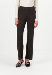 Brown, ribbed knit wide-leg trousers with an elastic waistband. Paired with black, pointed-toe flats. Smooth texture and fitted design.