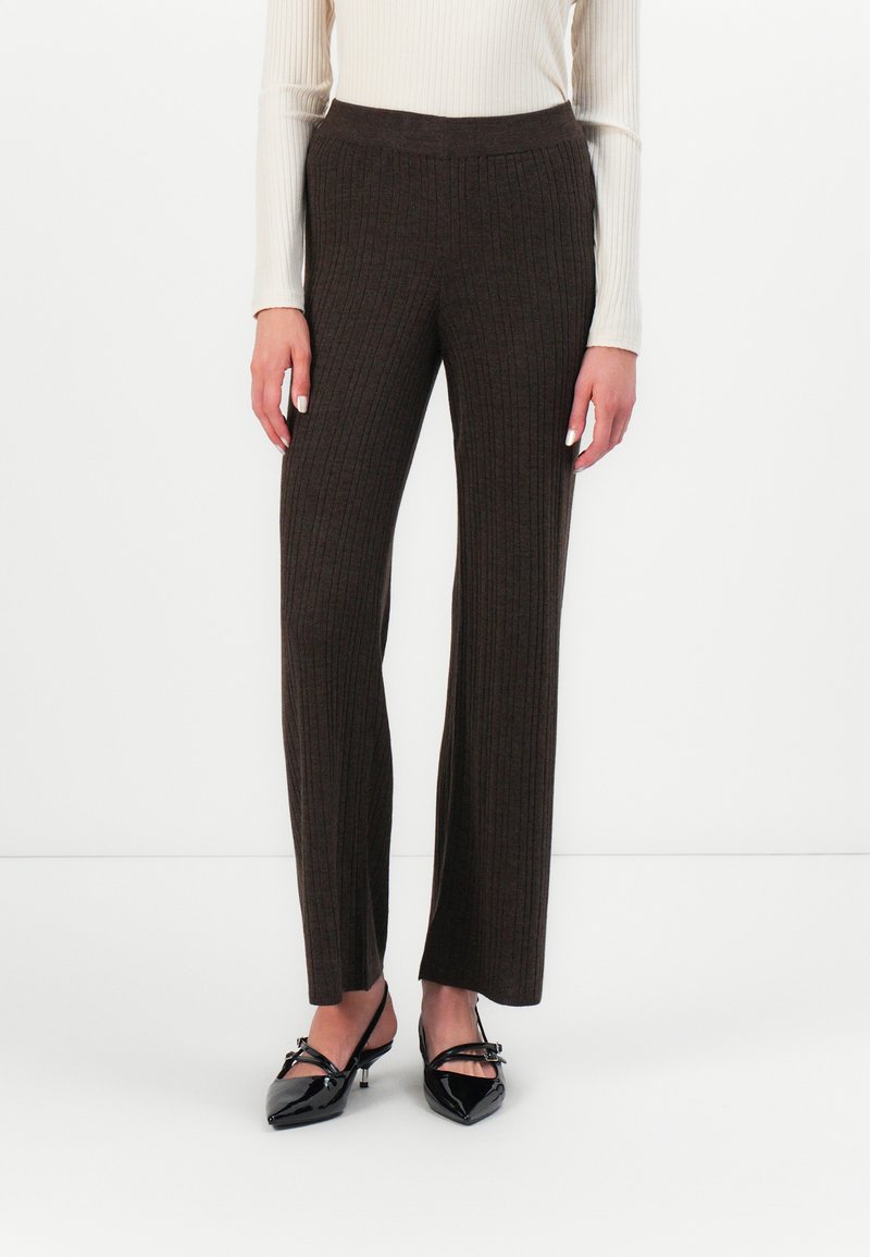 Brown, ribbed knit wide-leg trousers with an elastic waistband. Paired with black, pointed-toe flats. Smooth texture and fitted design.