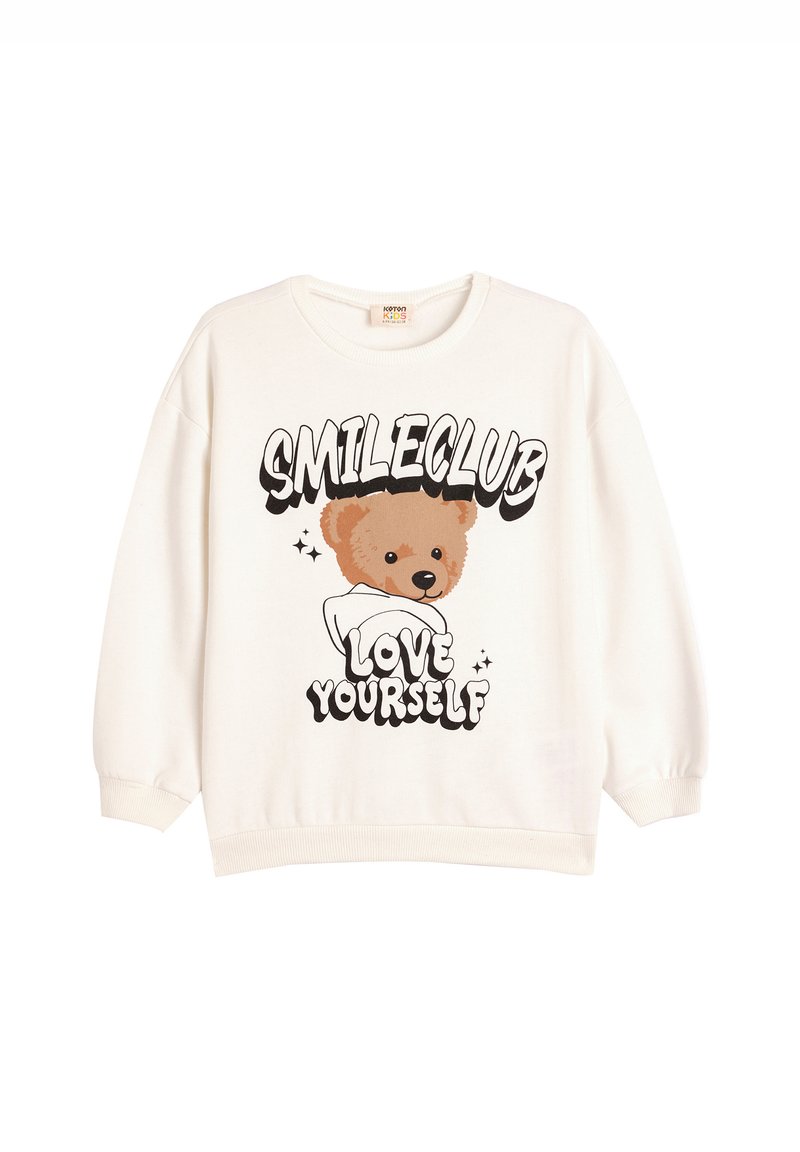 Sudadera color crema con un gráfico de un oso y el texto "SMILECLUB" y "QUIÉRETE A TI MISMO". Mangas acampanadas y cuello redondo.