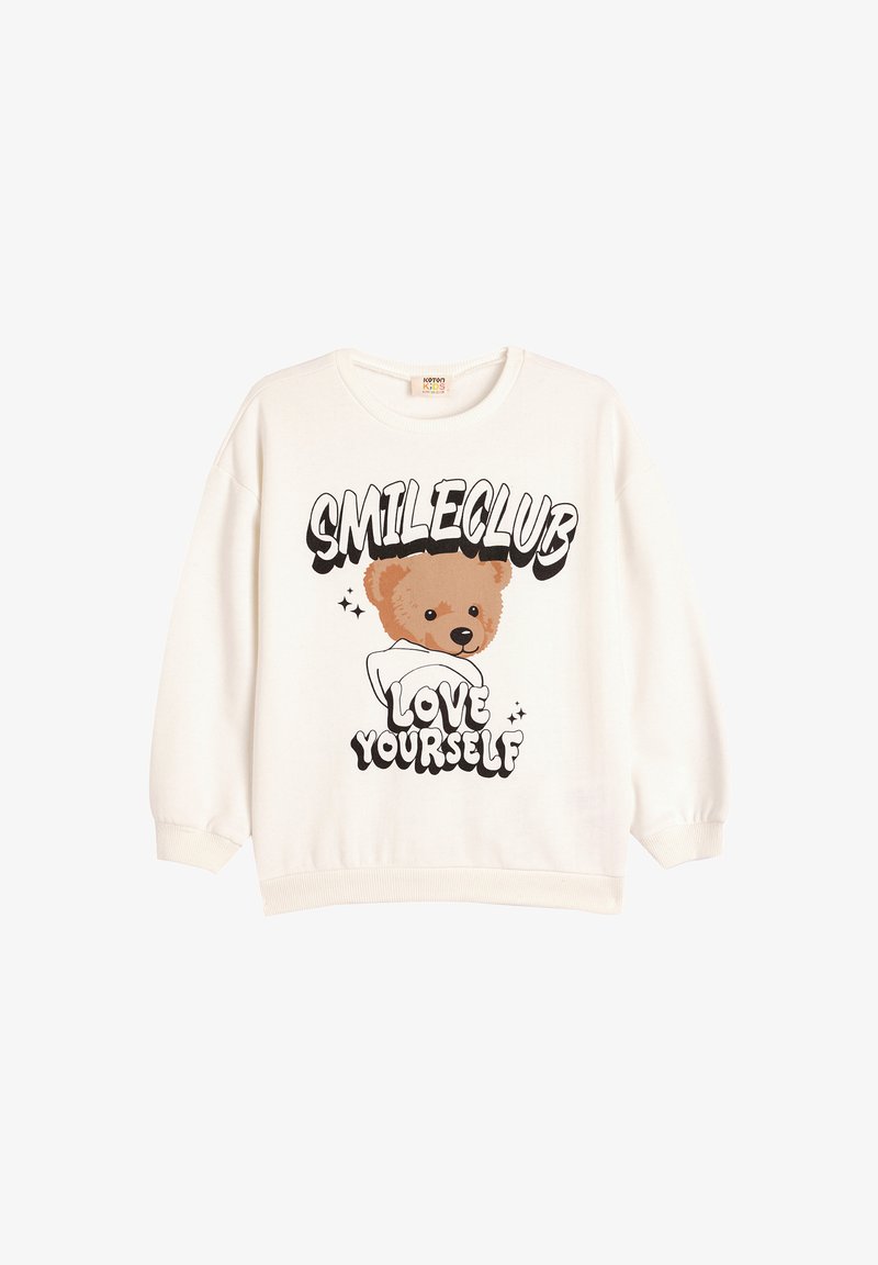 Sudadera color crema con un gráfico de un oso y el texto "SMILECLUB" y "QUIÉRETE A TI MISMO". Mangas acampanadas y cuello redondo.