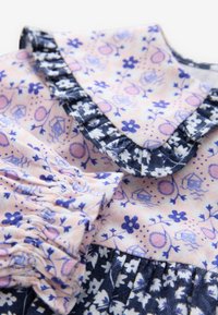 Õiekujundusega puuvillast kleit, mille värvikavaks on roosa ja mereväe sinine, volditud krae ja varrukad ning keerukad lille- ja kujundimustrid.