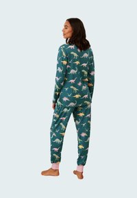 Grönt pyjamasset med färgglada dinosaurmönster, långärmad topp, nedtaperade byxor med rosa mudd, mjuk textur och avslappnad design.