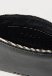 Zwart leren etui met ritssluiting en zilverkleurige hardware. Binnenkant bekleed met zwarte stof en voorzien van een merklabel.