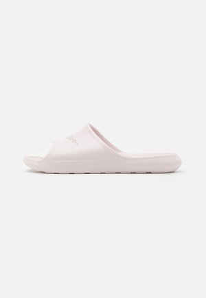 Light pink slide sandal made of textured rubber, featuring a wide opening and a flat sole, with a subtle logo on the strap.