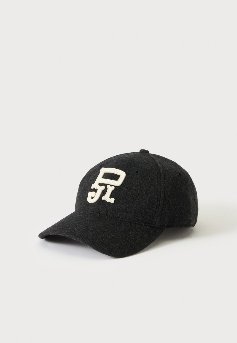 Casquette de baseball gris foncé avec une visière courbée et des lettres blanches stylisées brodées sur le devant sur fond blanc.