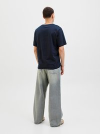 Námořnické bavlněné tričko s kulatým výstřihem, spárované s širokými džínami s světlým ombré efektem a minimálními detaily.