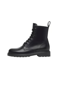 Bottine en cuir noir avec un bout rond, un laçage à l'avant et une semelle en caoutchouc robuste. Présente des coutures verticales et une languette à l'arrière.
