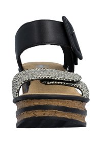 Vooraanzicht van een sleehak sandaal met kurkzool, een zwarte enkelriem met gesp, en een zwart-wit patroon op de stoffen teenriem.