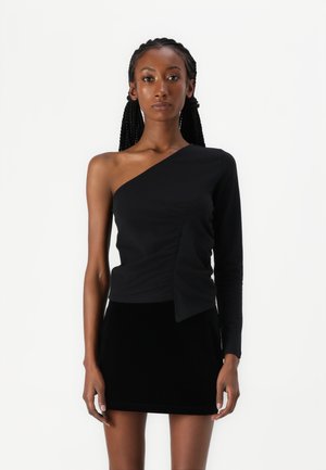 Haut noir à une épaule avec un détail froncé et une manche longue d'un côté, associé à une mini-jupe en velours noir.