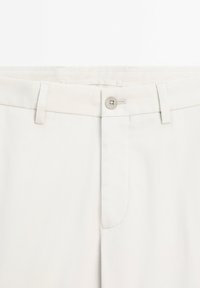 Helle beigefarbene Baumwollhosen mit Reißverschluss und Knopfverschluss, Gürtelschlaufen und einer einzigen vorderen Tasche mit sauberem Nähen.