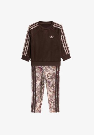 Brązowa, długorękawowa bluzka Adidas z wzorzystymi paskami na rękawach, połączona z legginsami w nadruk paisley z pasującymi brązowymi paskami.