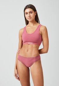 Roze sportbeha en bijpassende slips, gemaakt van zacht materiaal. De beha heeft een ronde halslijn en een logo-band; de slips hebben een delicate kantafwerking.