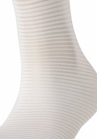 Hellbeige gestreifte Socke mit feiner, glatter Textur und dezenten vertikalen Linien, entworfen, um eng um den Fuß und Knöchel zu sitzen.