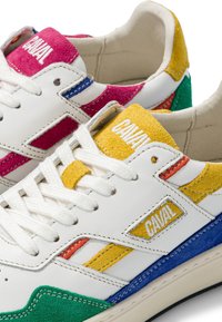 Baskets blanches avec des accents en suède jaune, vert, bleu, rouge et rose, et des lacets blancs, avec le nom de la marque "CAVAL" sur la languette et les côtés.