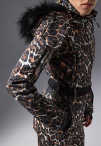 Parksuit med leopardmønster som har en tettsittende design, glidelåslommer og en hette med kunstig pelsdetalj, laget av et glatt og holdbart materiale.