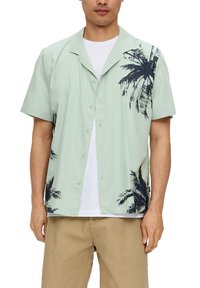 Korte mouwen overhemd met knopen in lichtgroen met een zwart palmbomenpatroon aan de linkerkant; gemaakt van gladde, lichte stof.
