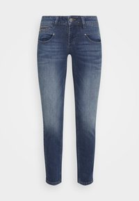 Jeans ajustados en denim azul oscuro con un lavado desvanecido. Presentan bolsillos frontales, cierre de botón metálico y acentos de tachuelas en la cinturilla.