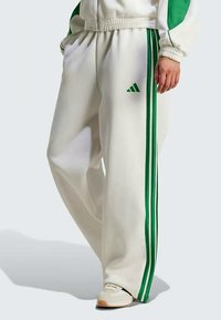 Λευρά παντελόνια φόρμας από μαλακό υλικό, με πράσινες λωρίδες στα πλάγια και λογότυπο Adidas. Ελαστική ζώνη για άνεση.