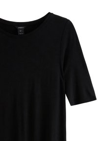 Svart kortärmad T-shirt med rund halsringning, tillverkad av slätt tyg med en subtil glans och en inre etikett som visar storlek och skötselanvisningar.