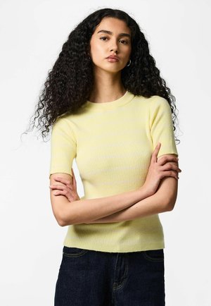 Top giallo a maniche corte con costine e strisce bianche, collo rotondo e design aderente, abbinato a pantaloni in denim scuro.