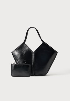 Bolso tote de cuero negro brillante con forma geométrica estructurada y pequeño neceser a juego con cremallera y correa para la muñeca sobre un fondo liso.