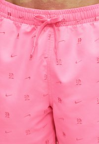 Φούξια μαγιό σορτς με ελαστική μέση, κορδόνι και κεντημένα μικρά λογότυπα Nike και στυλιζαρισμένα γράμματα "N" παντού.