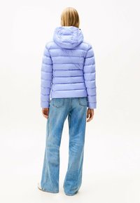 Lichtpaarse pufferjack met een capuchon, met horizontale strepen en elastische manchetten, gecombineerd met blauwe flared jeans.
