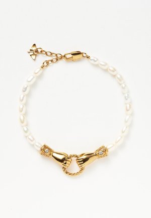 Bransoletka z pereł z dwoma złotymi dłońmi trzymającymi skręcony pierścień jako centralne zapięcie, z małą złotą kokardką na regulowanym łańcuszku.