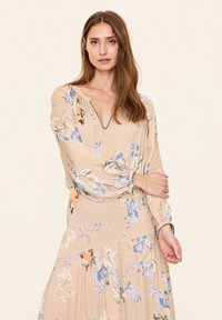 Beige Kleid mit Blumenmuster, V-Ausschnitt, langen Puffärmeln und gerafften Akzenten an den Manschetten und der Taille.