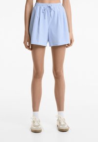 Shorts rayés bleu clair avec une taille élastique et un cordon de serrage, présentant une coupe décontractée et une texture de tissu douce.