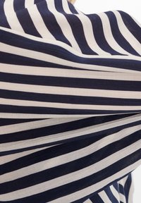 Marineblau- und weiß gestrefter Stoff mit strukturiertem Oberflächen, der abwechselnd dicke und dünne Streifen aufweist und in Falten drapiert ist.