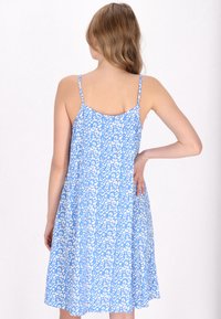 O rochie bleu fără mâneci, cu un model floral alb, având o croială lejeră și bretele ajustabile, care ajunge deasupra genunchiului.
