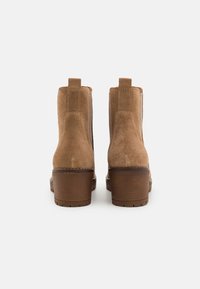 Tan zjemněné kožené kotníkové boty s hladkým povrchem, zaoblenou špičkou a vrstveným podpatkem. Obsahují boční elastické panely pro snadné obouvání.