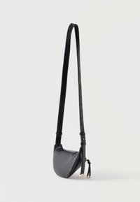 Μικρή μαύρη δερμάτινη τσάντα χιαστί με μακρύ ρυθμιζόμενο λουράκι και φουντίτσες από φερμουάρ σε χρυσό τόνο σε λευκό φόντο.