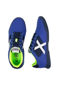 Zapatillas deportivas azules con paneles laterales de malla, logo blanco y acentos verdes. Presentan una suela gruesa, detalles texturizados y diseño de cordones. Tamaño 42.