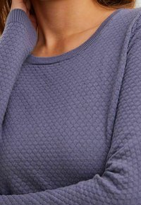 Pull violet en tricot arborant un motif en nid d'abeille texturé, avec un col rond et des manches longues.