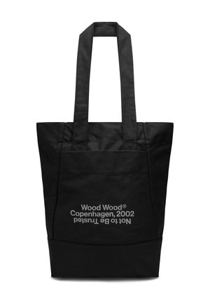 Sort stof tote bag med to robuste håndtag. Har en frontlomme med hvid tekst, der læser "Wood Wood Copenhagen, 2002 ikke til at stole på."