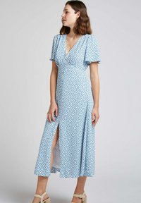 Robe midi bleue à fleurs avec des manches courtes et flottantes, décolleté en V, fente sur le côté et tissu léger, présentant un délicat motif floral.
