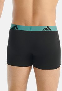 Černé boxerky s tyrkysovým pasem a černým logem. Tkanina je hladká, s přiléhavým střihem a minimálním počtem švů.