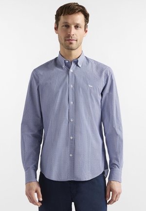 Camicia con bottoni a fantasia blu e bianca, maniche lunghe, collo classico e piccolo logo sul petto. Tessuto dalla texture liscia.