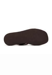 Semelle de chaussure avec une surface en caoutchouc noir texturé, présentant une forme arrondie, un design plat, et sans motifs ou détails de quincaillerie supplémentaires.